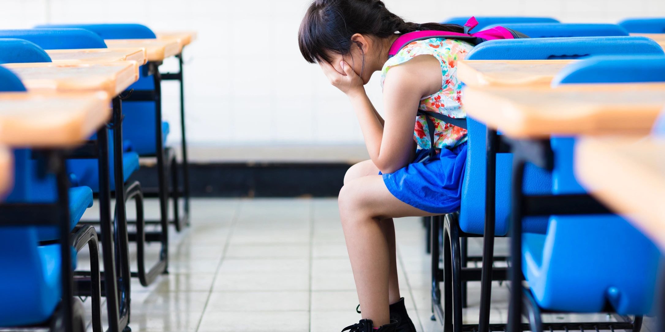 A sad girl sitting inside a classroom