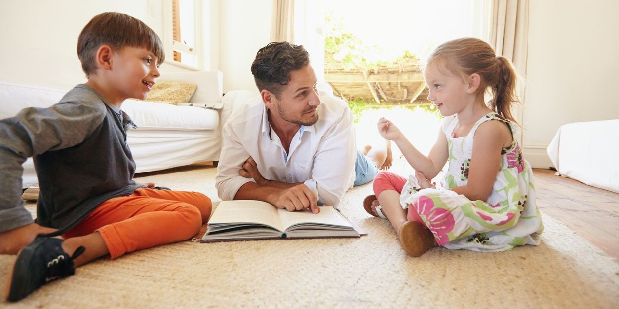 A man and two children are sitting on the floor